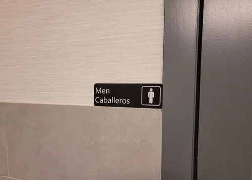 Vista 4 de Juego de letreros para baño con adhesivo en español e inglés - 9" x 3" - Hombres/Caballeros y Mujeres/Damas -Juego de dos letreros- Negro con letras
