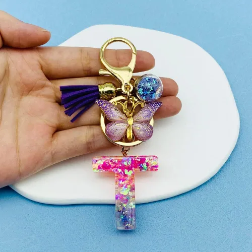 Vista 5 de Llaveros con letras iniciales para mujeres y niñas, mochila con resinas, letras del alfabeto, llaveros de coche, bola de mariposa, borla con dije