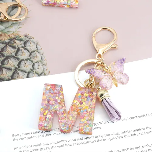 Vista 2 de OKAICEN Llavero con letra inicial del alfabeto diseño de copos de nieve con borlas color morado para bolsos mujeres y niñas