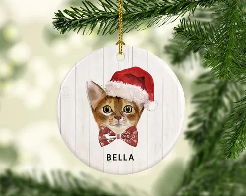 Vista 2 de Andaz Press Adorno redondo personalizado de cerámica para árbol de Navidad, abisinio, corona de acebo, sombrero de Papá Noel, con gráfico de gato