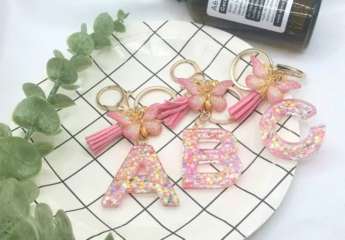 Vista 2 de Meefisher Llavero de letra inicial de mariposa con borla rosa púrpura y estrella, para cartera, monederos, mochila, bolsos, alfabeto, llavero