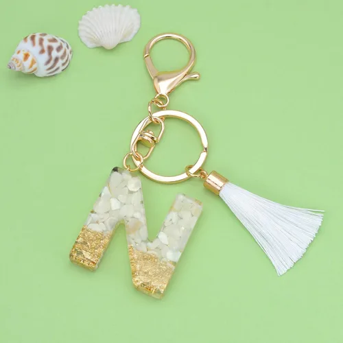 Vista 2 de Suweibuke Lindos llaveros beige para mujeres y niñas, llaveros con letras iniciales con borla blanca, dijes para mochila y bolso de mano