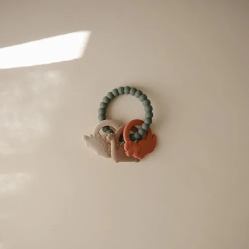 Vista 2 de mushie Anillo de dentición de dinosaurio de silicona de juguete