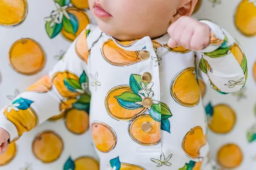 Vista 4 de Funda ajustable para cambiador de flores de naranja, hecha de viscosa de bambú y elastano, se adapta a cambiador estándar, por Florida Kid Co.
