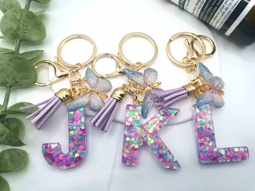 Vista 3 de Llavero con letra inicial del alfabeto de resina morada, azul, rosa, borla, mariposa, llavero para bolso, cartera, bolso, llaves del coche