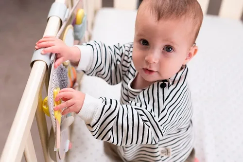 Vista 2 de Taf Toys Tablero de actividades para recién nacidos y niños pequeños con música y luces, 13 actividades Montessori, espejo seguro para bebés